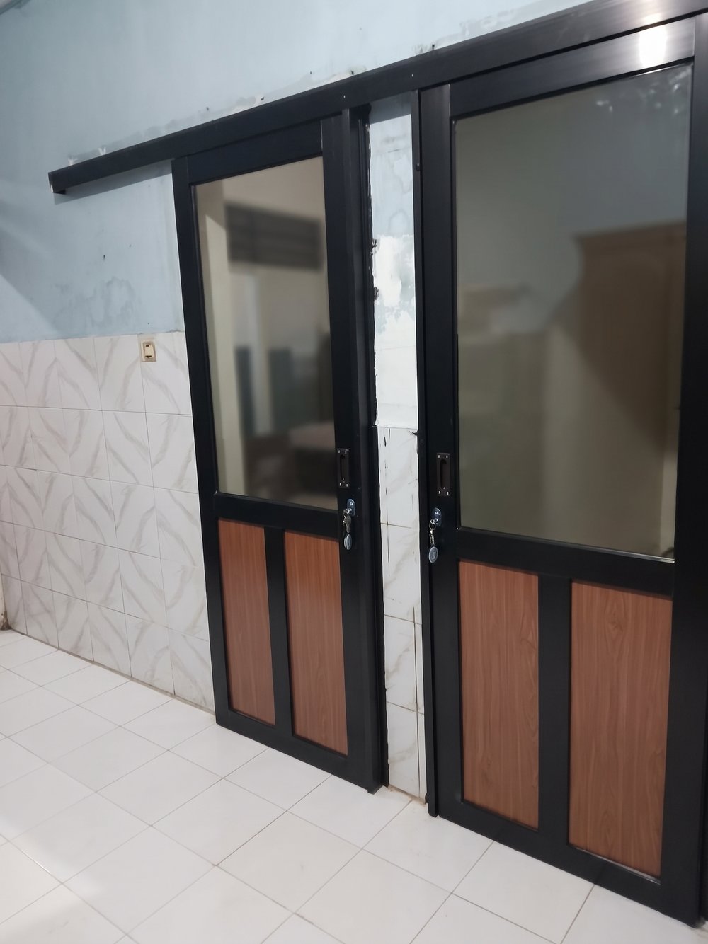 Dua pintu sliding aluminium hitam, bagian atas kaca dan bagian bawah panel ACP motif kayu